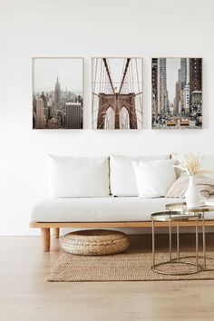 a living room with white couches and pictures on the wall above them, along with a coffee table