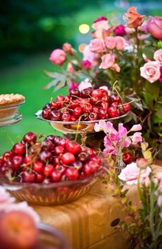 there are many different types of flowers and fruit in bowls on the table, including strawberries