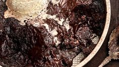 a bowl filled with ice cream and brownies on top of a wooden table next to a spoon