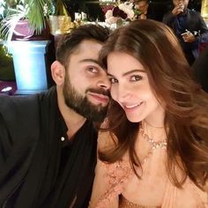 a man and woman are posing for a picture at a restaurant table with people in the background