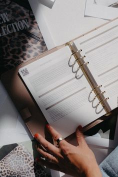 a person holding a ring on top of an open book next to other books and papers