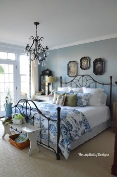 a bed room with a neatly made bed and a chandelier hanging from the ceiling