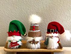 three knitted santa hats sitting on top of a wooden tray