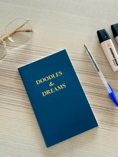 a pair of glasses, eyeglasses and a book sitting on a table next to some pens