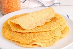 a stack of corn tortillas on a plate next to a jar of mustard