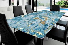 a dining room table with blue and gold paint on the top, surrounded by black chairs