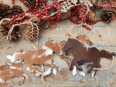 three wooden horses are laying on the ground next to pine cones