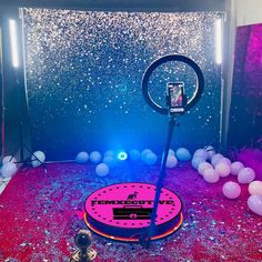 a pink and blue stage set up for a party with balloons, lights and confetti