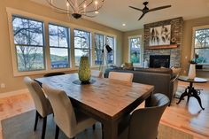 a dining room table with chairs and a vase on it in front of a fireplace