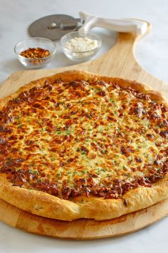 a pizza sitting on top of a wooden cutting board next to other food dishes and utensils