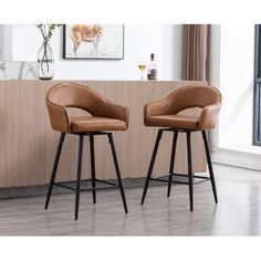 two brown leather bar stools sitting in front of a counter top with a painting on the wall