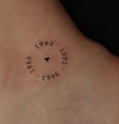 a small clock tattoo on the back of a woman's left foot, with numbers written in black ink