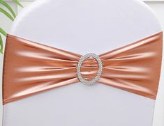 the back of a white chair with a rose gold sash and ring buckle on it