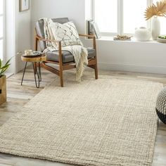 a living room area with a chair, rug and potted plant in the corner