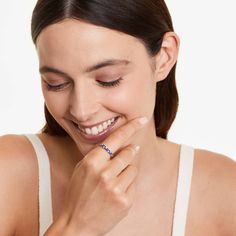 a woman smiles as she holds her hand to her face and wears a diamond ring