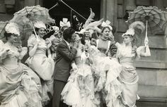 an old black and white photo of people dressed in fancy clothing, kissing each other