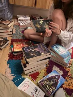 a woman is sitting on the floor surrounded by books