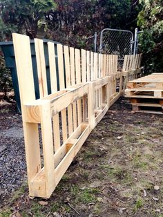 a wooden bench made out of pallets in the grass next to some bushes and trees