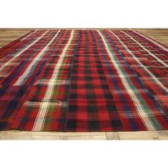 a large red and black plaid rug on wooden floor with wood floors in the background