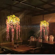 a dining room with wooden tables and chairs covered in pink flowers hanging from the ceiling