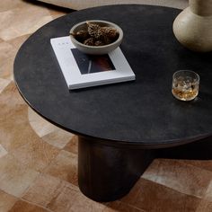 a coffee table with a book, glass and vase on it next to a couch