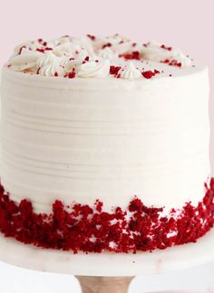 a white cake with red sprinkles sitting on top of a wooden stand