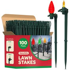 the lawn stakes are green and have christmas lights on them in front of an open box