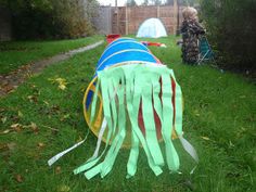 a child is playing in the grass near a tent and some kites that have been tied to it