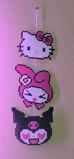 two hello kitty pinatas are hanging on a wall with pink and purple background