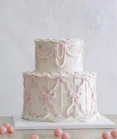 a three tiered cake with pink icing and bows on the top, sitting on a table