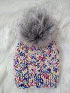 a multicolored knitted hat with a pom - pom on top