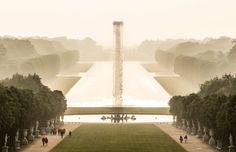 an aerial view of a park with trees and people walking on the grass near water