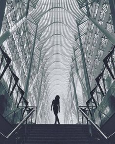 a person walking up some stairs in a building with lots of metal structures on the ceiling