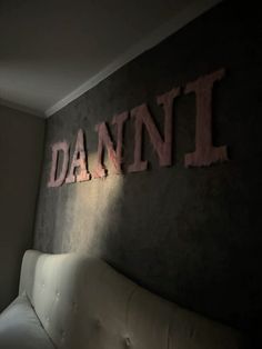 a white couch sitting in front of a wall with the word danni on it