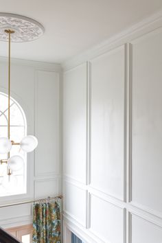 the interior of a house with white walls and wood flooring, including a chandelier