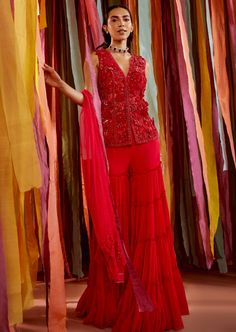 Red tonal hand embroidered kurta featuring 3D organza flowers, it has a v-neckline, half lining. It is paired with a tiered sharara in georgette and a net dupatta. It is our version of a fuss-free fun sari. Just zip up, cinch it with a belt and dance away! Red Sharara, Pink Sharara, Sleeveless Kurta, Indian Bridesmaids, Hot Pink Floral, Traditional Styles, Organza Flowers, Sanya, Sharara Set