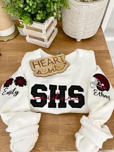 ** Please read before buying **  Personalized Embroidered School Spirit sweatshirt with glitter HTV applique. Fit: Unisex, Fits loose/relaxed Sizing: S,M,L,XL,2XL Material: 50% Cotton, 50% Polyester Embroidery Details: School initials with mascot name centered across the chest Pom pom's with personalized name on right shoulder sleeve Helmet with personalized name on left shoulder sleeve *If you don't see what you're looking for please message me. :)  PROCESSING/TURNAROUND TIME: -Processing/Turn Football School Shirts, Multi Sport Mom Shirt, Cheer Mom Sweatshirt Ideas, School Sweatshirts Designs, Cheer Camp Outfits, Cheer Sweatshirts, Cheer Jackets, Football Merch, Senior Things