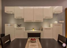 a dining room table and chairs in front of white cabinets