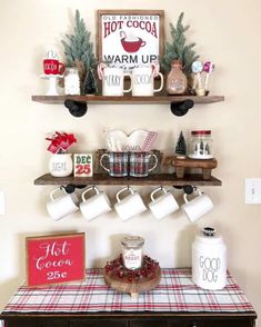 a table topped with cups and mugs next to a shelf filled with christmas decorations