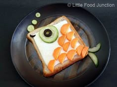 a piece of toast with vegetables and an olive on it is sitting on a plate