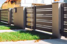 the fence is made of metal and has vertical slats on it, along with green grass