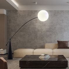 a living room with a couch, coffee table and lamp in front of the wall