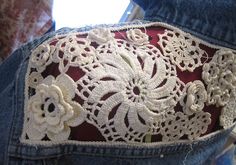 a pair of jeans with crocheted lace on them and flowers in the back pocket