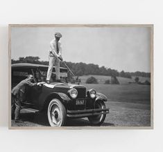 a man standing on top of an old car with another man in the back seat