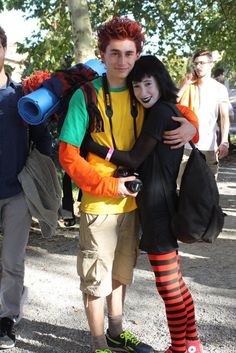 two people dressed in costumes standing next to each other on a sidewalk with one person wearing a backpack and the other holding a camera