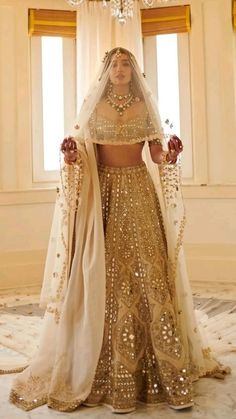 a woman in a gold and white bridal gown standing next to a chandelier