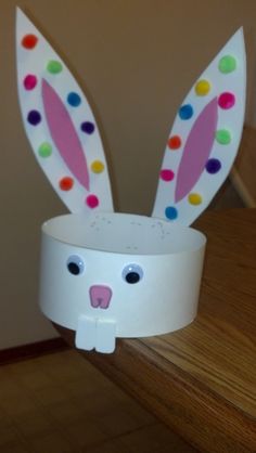 an easter bunny made out of toilet paper on top of a wooden table next to a wall