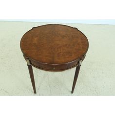 a round wooden table with two legs and a circular top, on a white carpeted floor