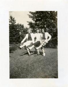 an old black and white photo of four people playing frisbee in the grass