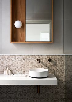 a white sink sitting under a bathroom mirror next to a wall mounted faucet